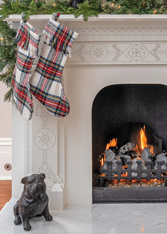 Plaid stockings hanging on a fireplace, above a statue of a bulldog