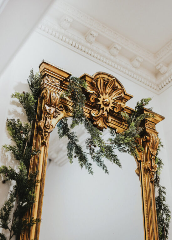 Holiday greenery draped around an elaborate gold mirror