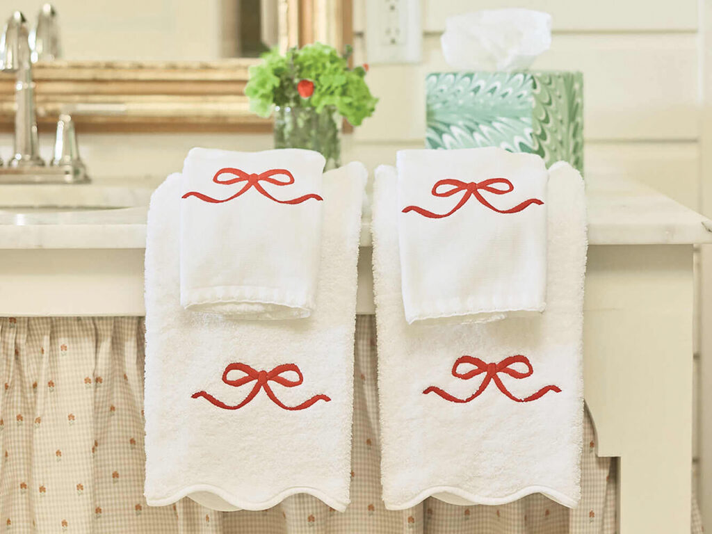 White scalloped hand towels with red embroidered bows on a bathroom sink