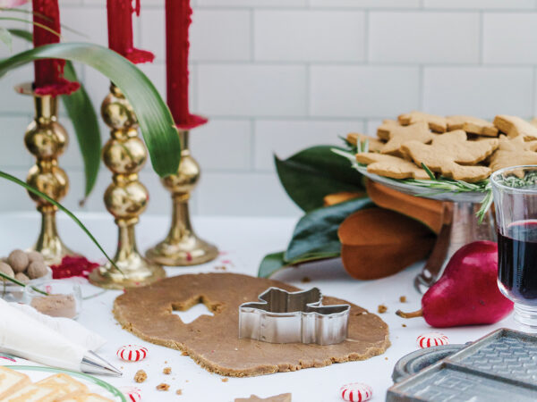 Gingerbread cookie-making supplies on a white stone countertop with a white subway tile backsplash