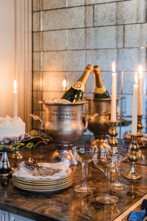 Champagne, champagne glasses, candles, cake, cake plates and forks on a marble countertop