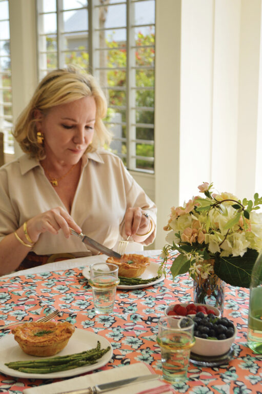 Middle-aged blonde woman sitting at a table and cutting a small pie