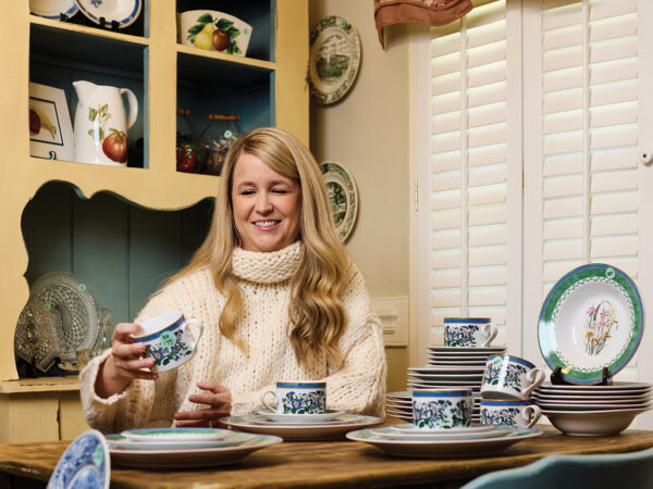 A blond woman wearing a chunky cream sweater sitting at a kitchen table