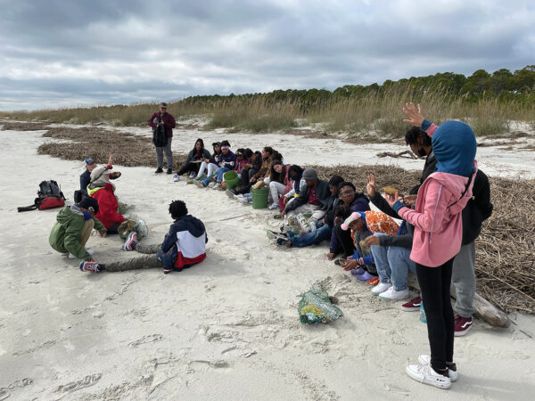 Students and teacher having class on a beach