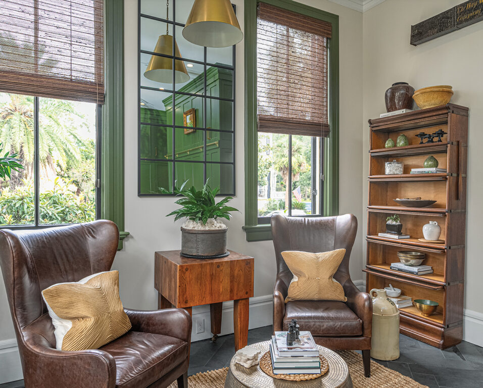 A sitting area with dark leather chairs and a butcher block end table in a large modern kitchen in a Victorian home