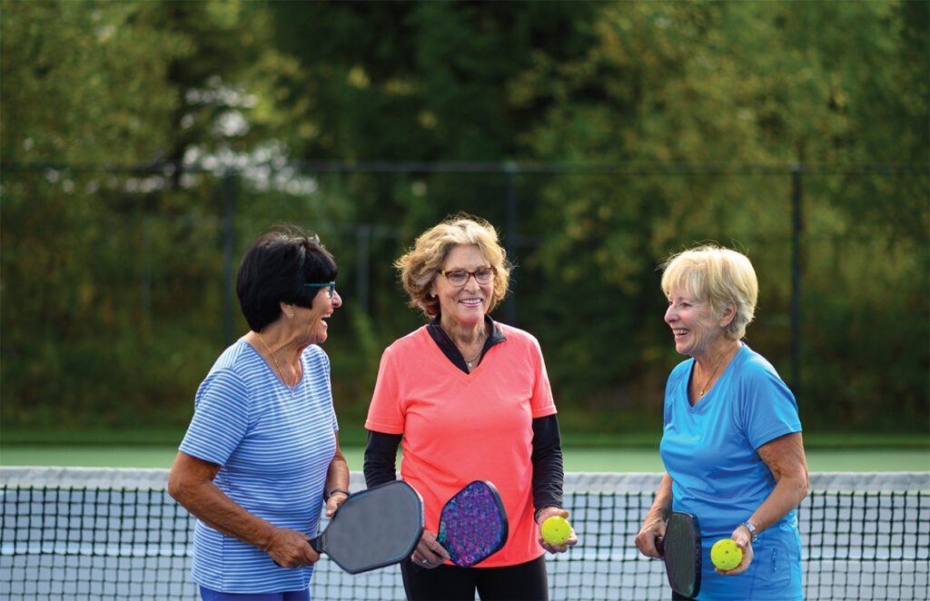 Three older women playing pickleball