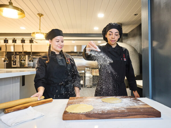 Two young women making pastries at a culinary school