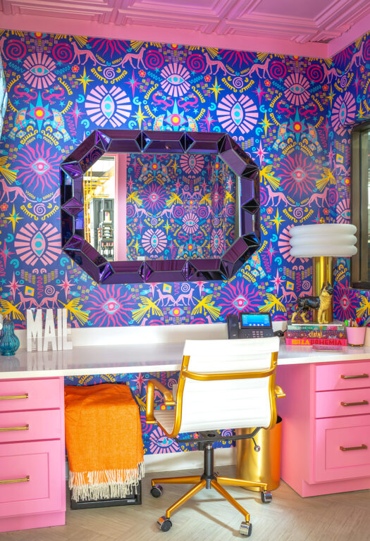office with bright pink cabinets and ceiling and bright, pink, blue, red, and yellow patterned wallpaper