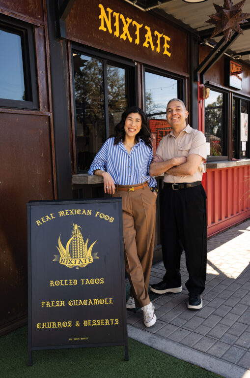 Owners of Nixtate standing in front of the restaurant's entrance