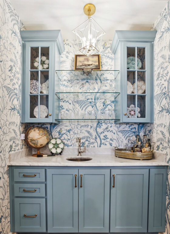 wet bar with light blue cabinets and wallpaper with a light blue plant design