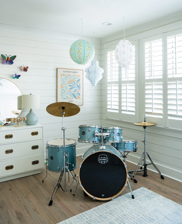 blue drum set in a girl's room with paper lanterns hanging from the ceiling and white shiplap walls