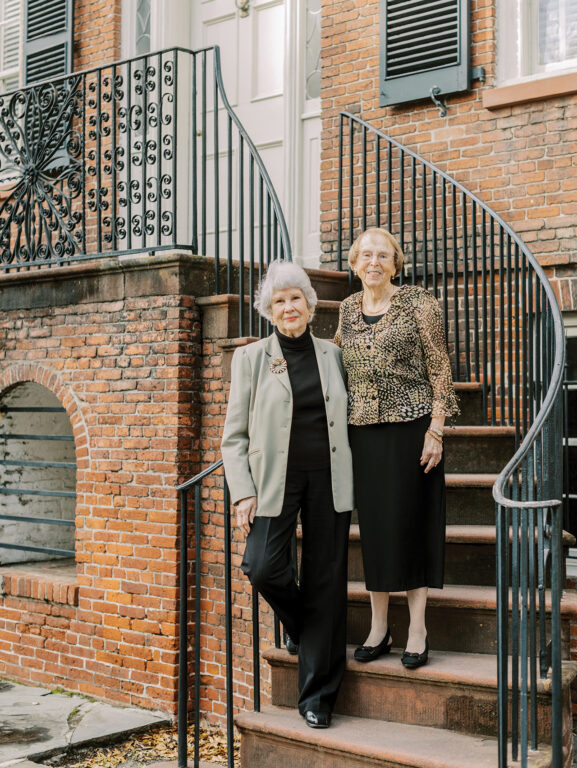 Two older women standing on steps together
