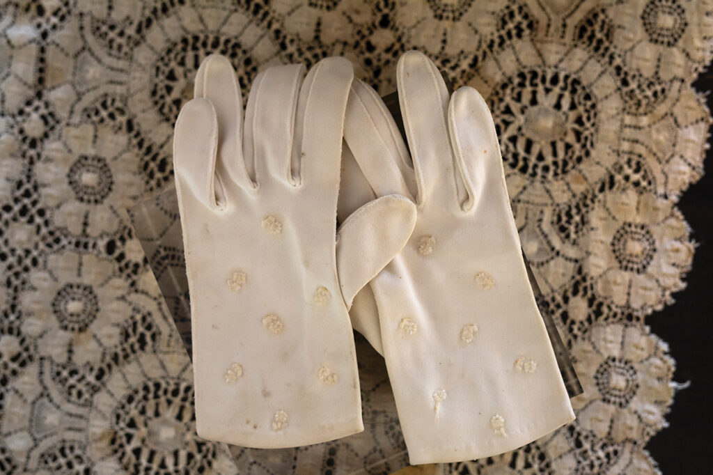 A pair of white satin gloves lying on a lace doily