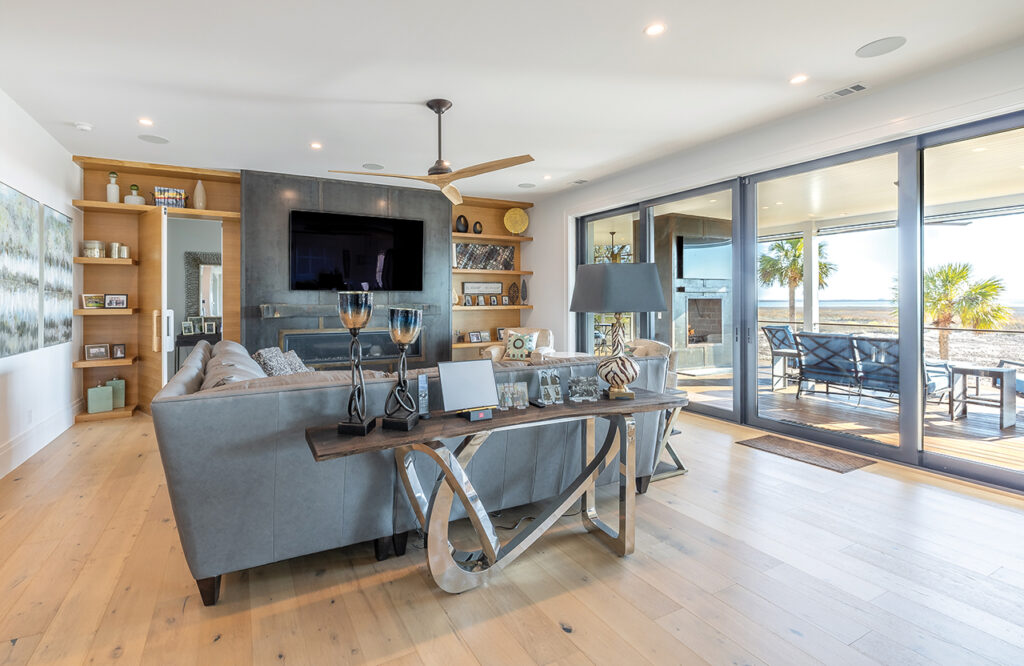 Family room with wood floors and one wall of sliding glass doors that looks out onto the patio and the marsh