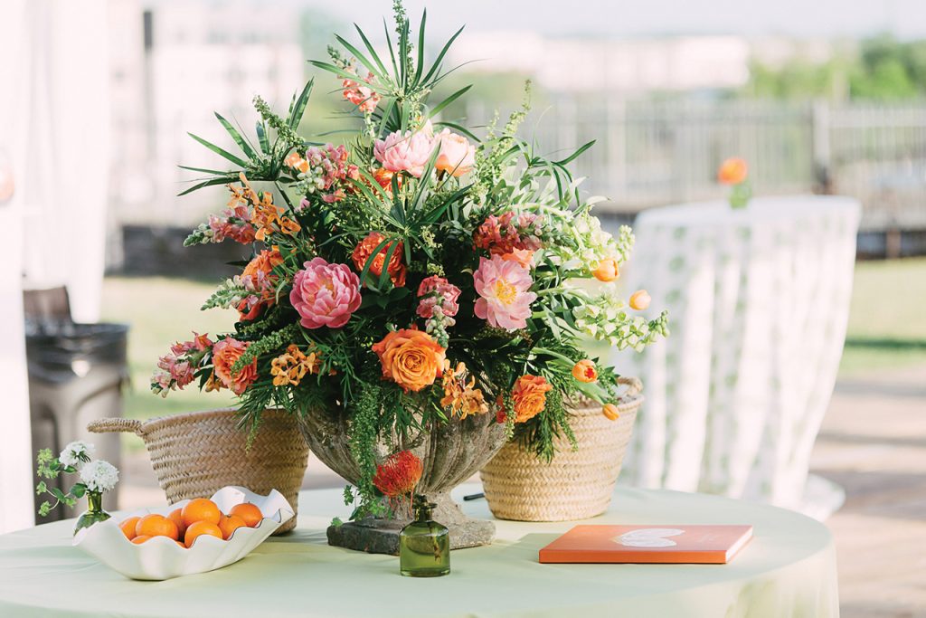 A colorful flower arrangement next to a scalloped bowl of clementines