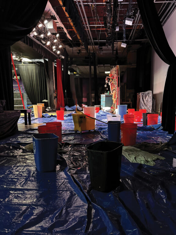 theater stage covered in tarps and buckets to catch leaks