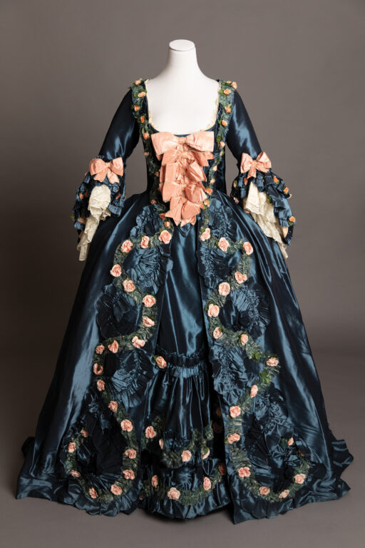 A dark blue Victorian dress with peach bow and flowers from “Dangerous Liaisons”