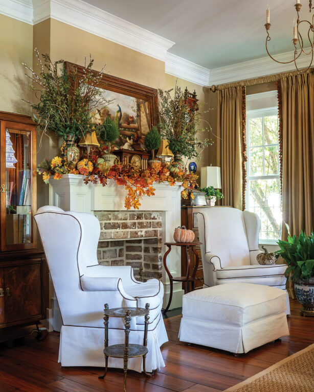 A living room with white wingback chairs and a fireplace