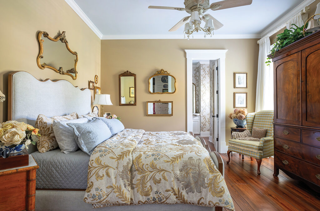 A bedroom with an upholstered bed and antique armoire