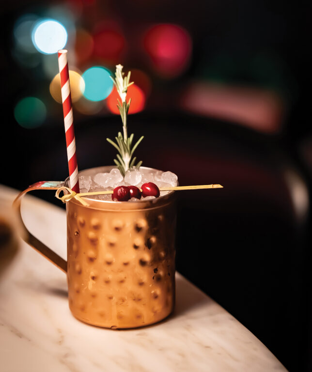 a yule mule with a red-and-white striped straw and cranberry garnish