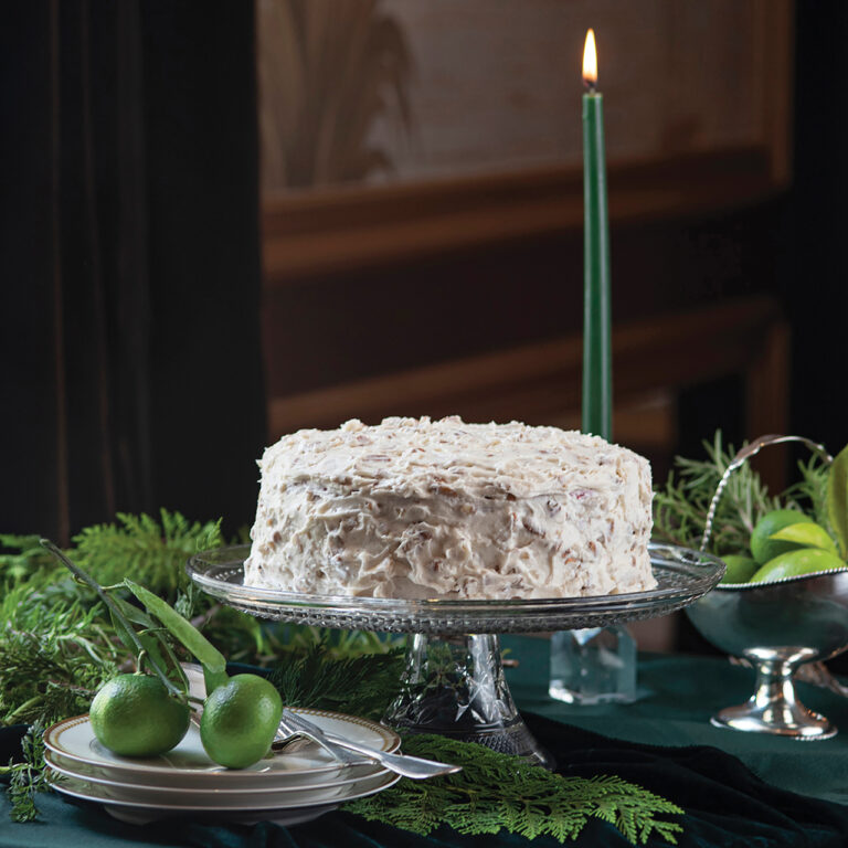 A cake with cream cheese frosting sitting on a cake stand