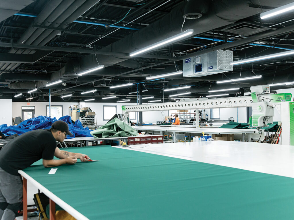 a man cutting a huge piece of green fabric