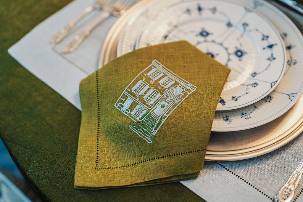 A green linen napkin with a home's facade printed on it