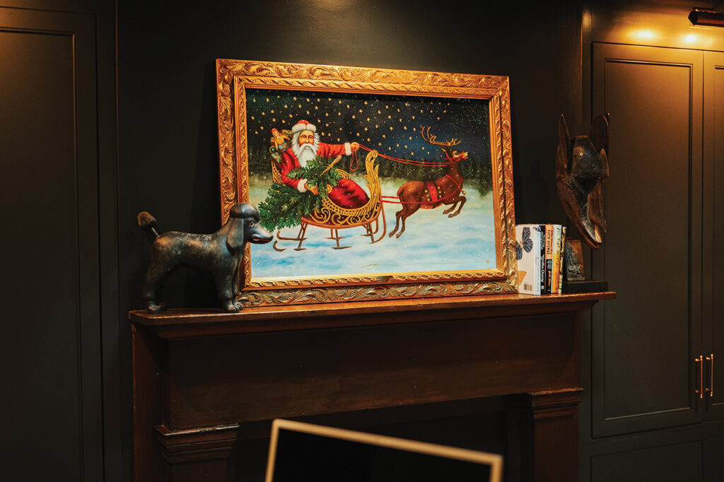 A painting of Santa in a gold frame sitting on top of a fireplace mantle