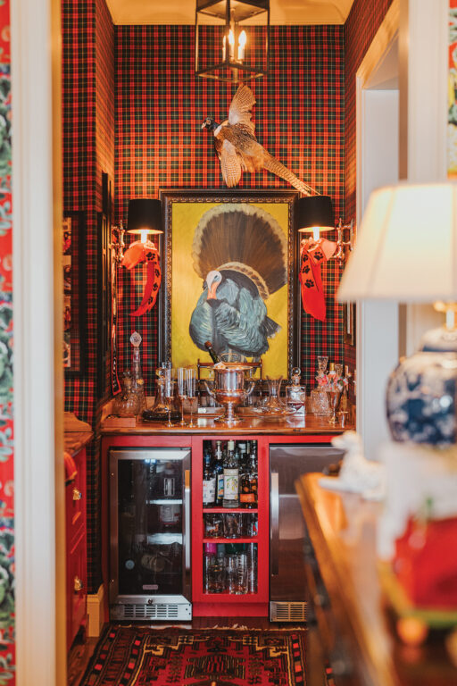 A bar nook in a butler's pantry with red-and-black plaid wallpaper and a painting of a turkey