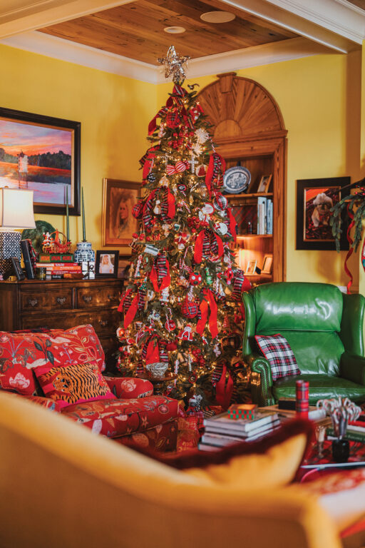A Christmas tree in a living room with yellow walls, heart pine ceilings, and heart pine book cases.