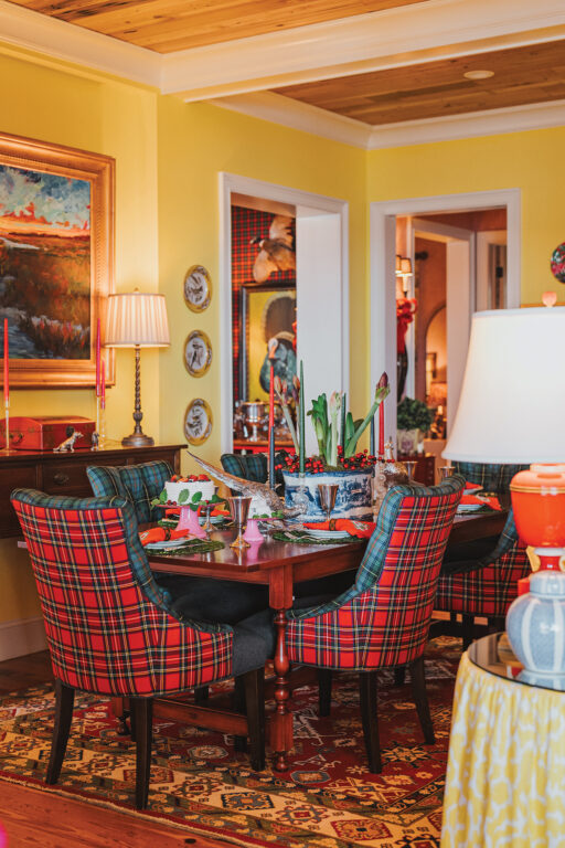 A dining room with yellow walls, heart pine ceiling, and red-and-green plaid dining chairs