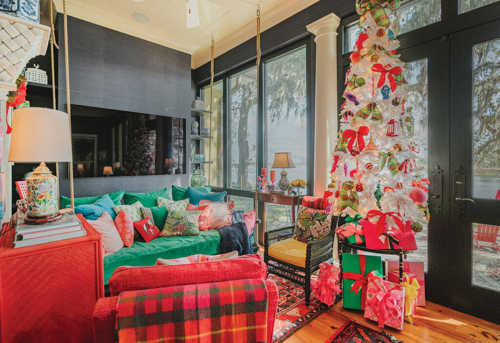 A white Christmas tree on a closed in patio with green and red furniture