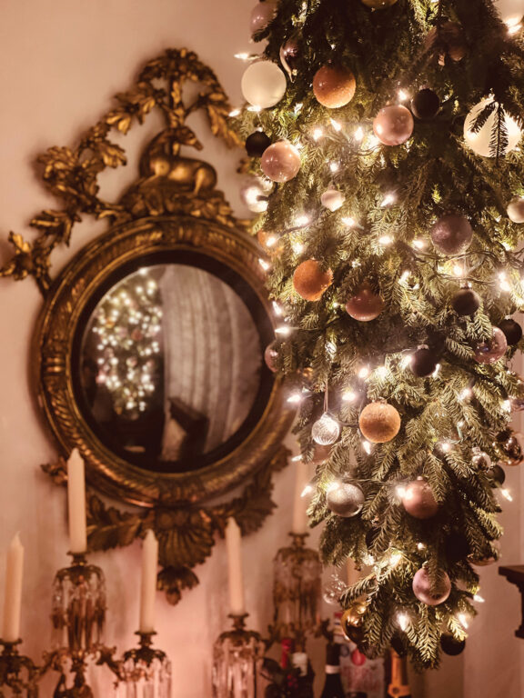 an evergreen bough decorated with white lights and white and silver ornaments