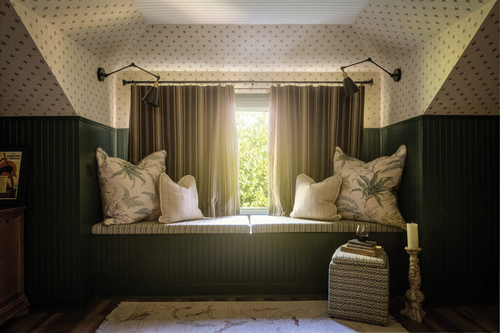 a window seat in a bedroom with hunter green beadboard walls