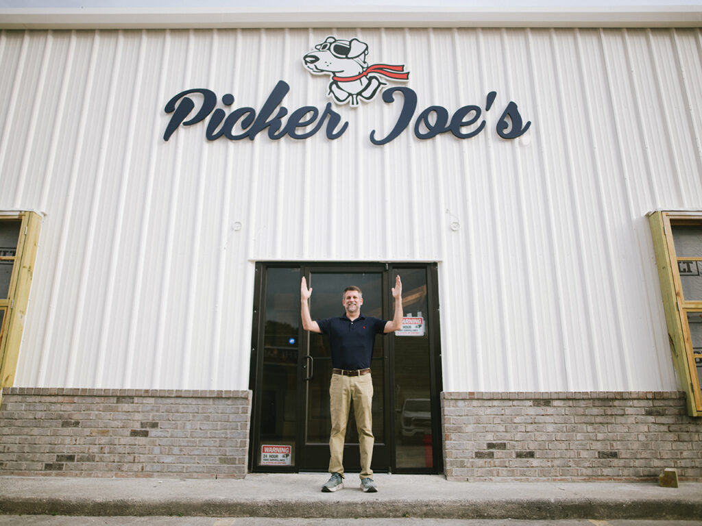 man standing with his arms up in front of a warehouse