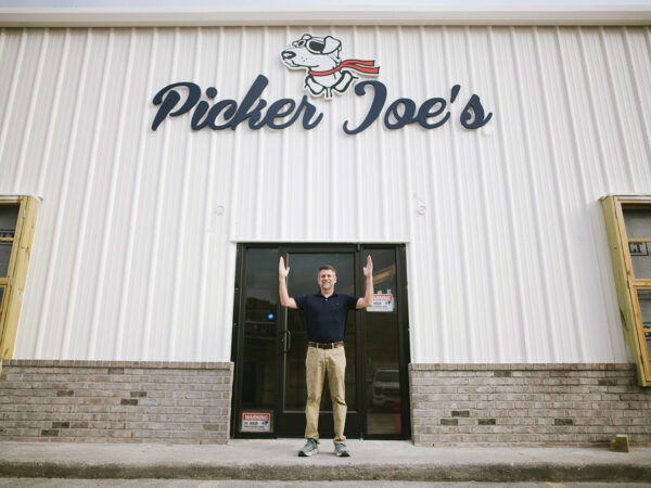 man standing with his arms up in front of a warehouse