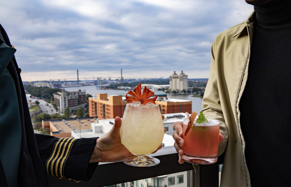 Two people holding cocktails on a rooftop bar