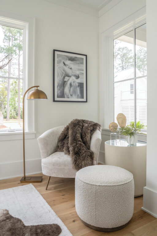 A cozy nook with a chair, footrest, brass floor lamp, and a fur throw
