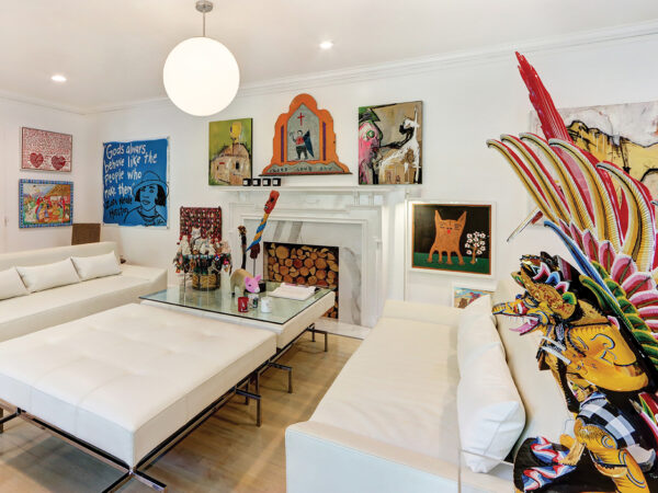 Numerous works of art displayed in a living room with white walls and white leather furniture