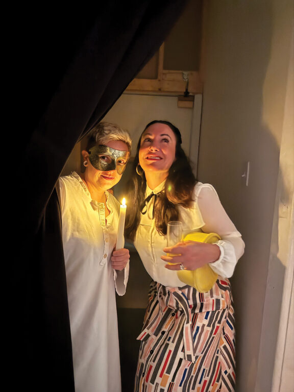 Two women peeking from behind a curtain