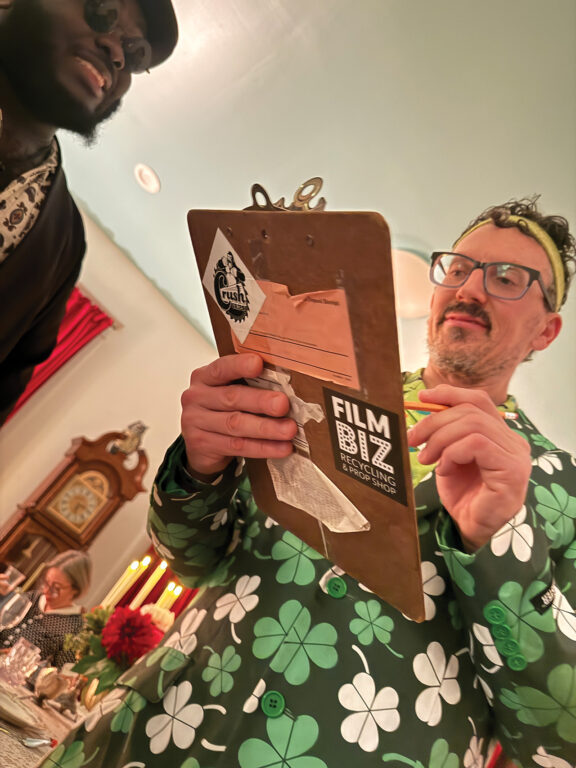 Man in a suit with shamrocks printed on it and holding a clipboard