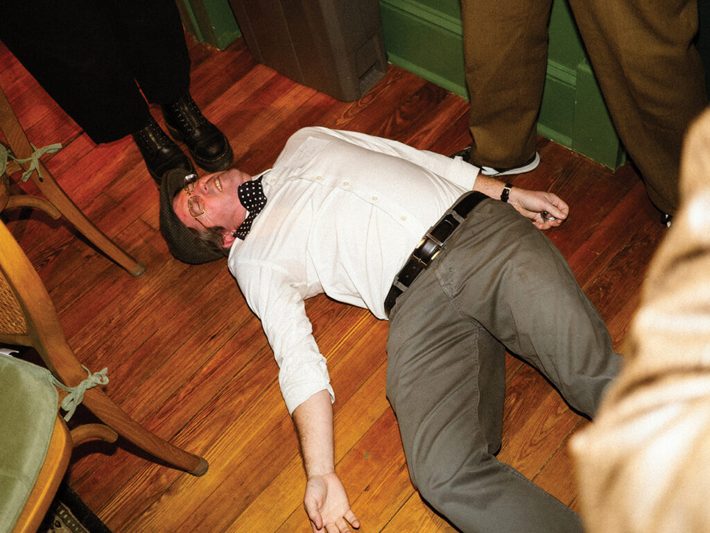 the victim lying on the floor during a murder mystery show