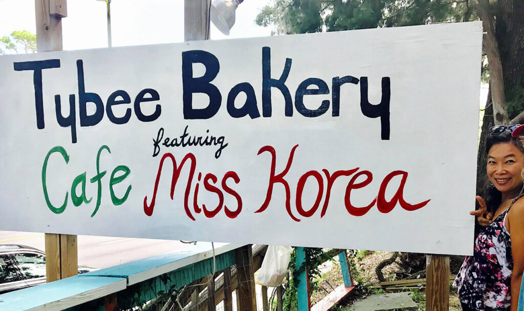 Jeeyun Lee standing in front of the sign to her cafe on Tybee Island