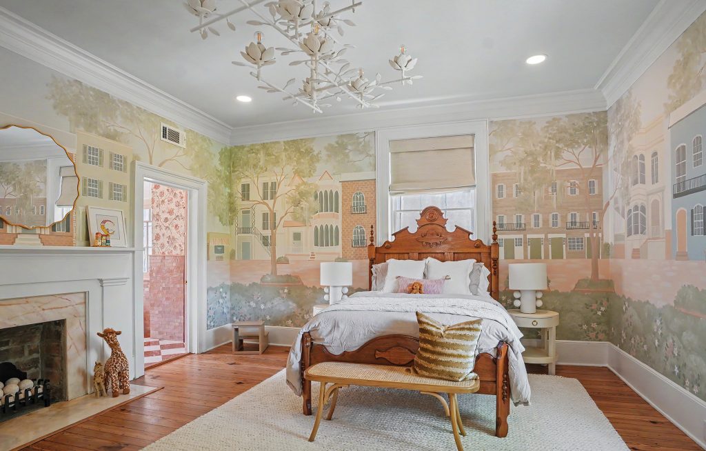 a girl's bedroom with a vintage bed, a hand-painted mural depicting a Savannah scene, a pink marble fireplace, and a white bird-and-flower-themed chandelier