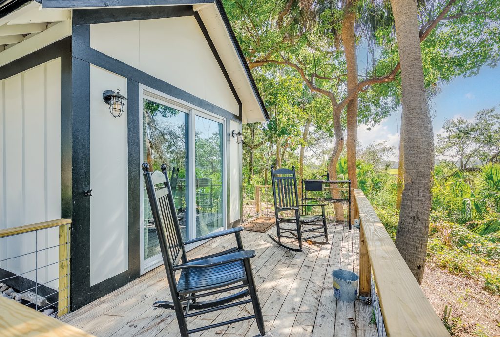 Two black rocking chairs on a deck overlooking the marsh